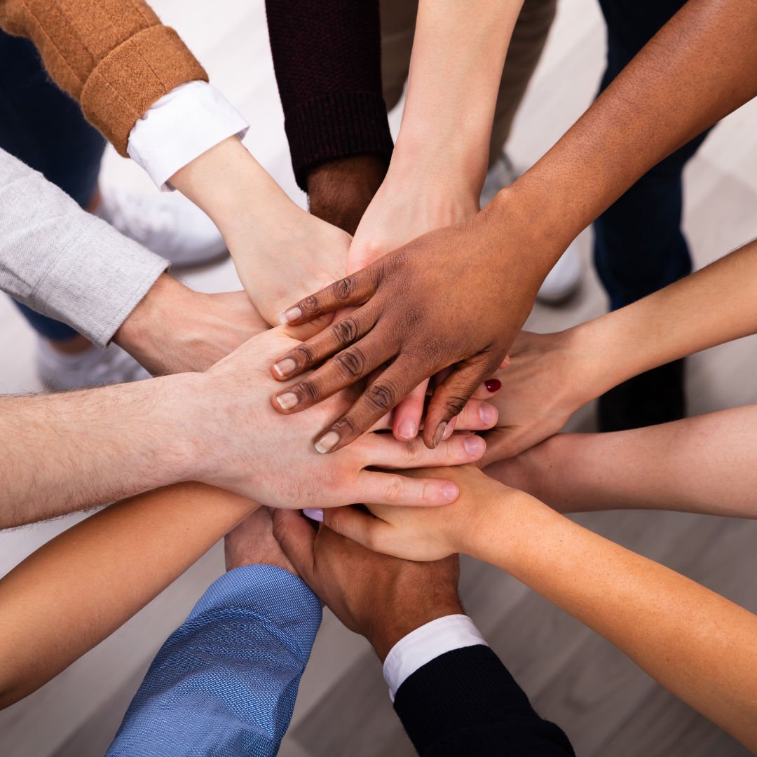 Several people put their hands together in a show of solidarity.